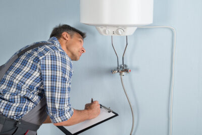 portrait of male plumber holding clipboard looking at electric boiler